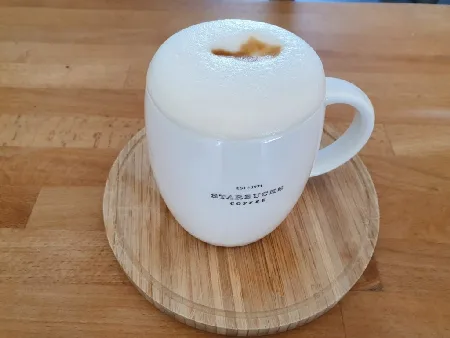 Schöne Starbucks Tasse, schöner Untersteller aus Holz und leckerer Milchkaffee mit Hafermilch!